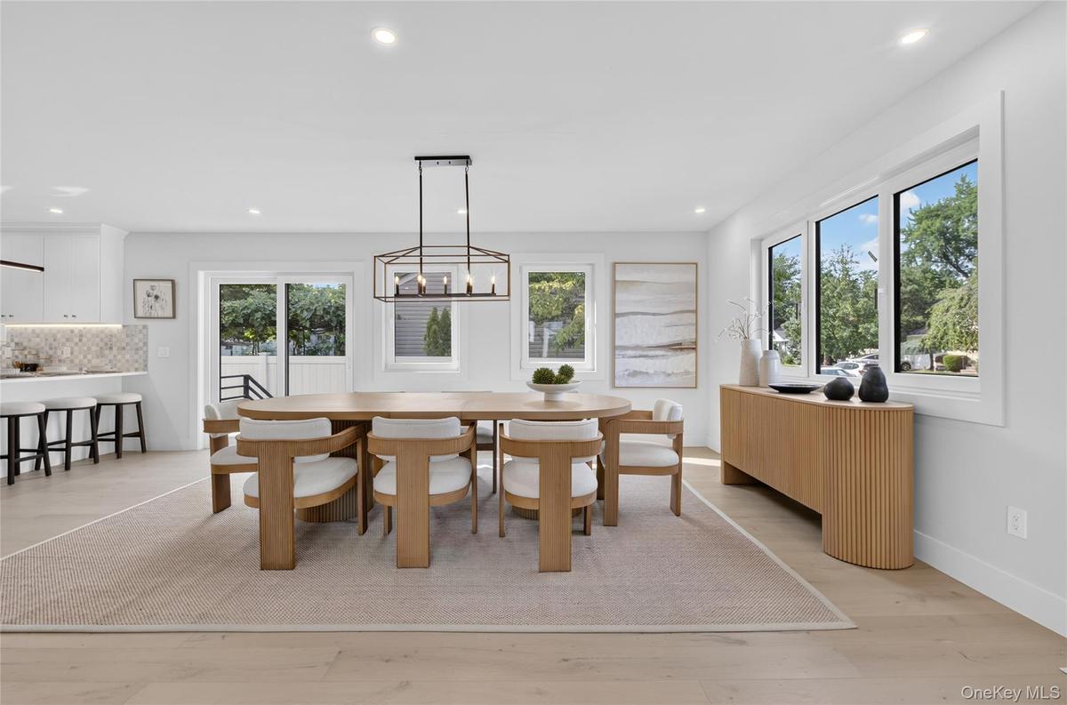 Recessed lighting, wood-finish flooring, a contemporary linear chandelier, multiple large windows, and white walls