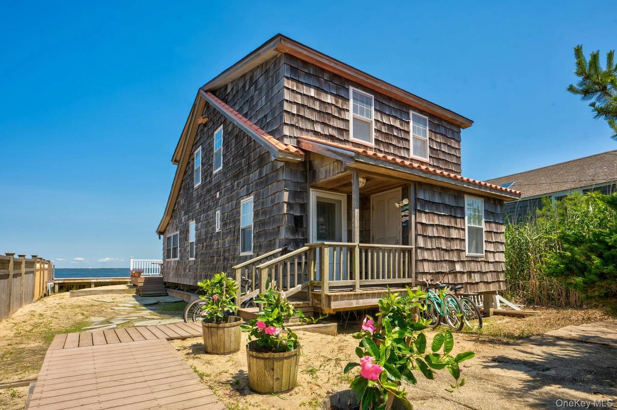 Two-story shingle-sided residence featuring a covered front porch with wood railings