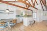 Kitchen featuring a breakfast bar, white appliances, light countertops, white cabinetry, and high vaulted ceiling