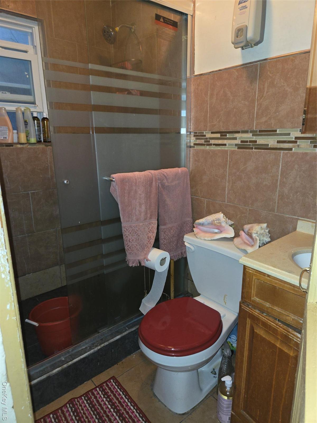 Bathroom with a stall shower, vanity, tile patterned floors, and tile walls