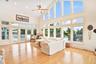 Living area featuring high vaulted ceiling, french doors to two decks, ight wood-style flooring, healthy amount of natural light, a ceiling fan, and r