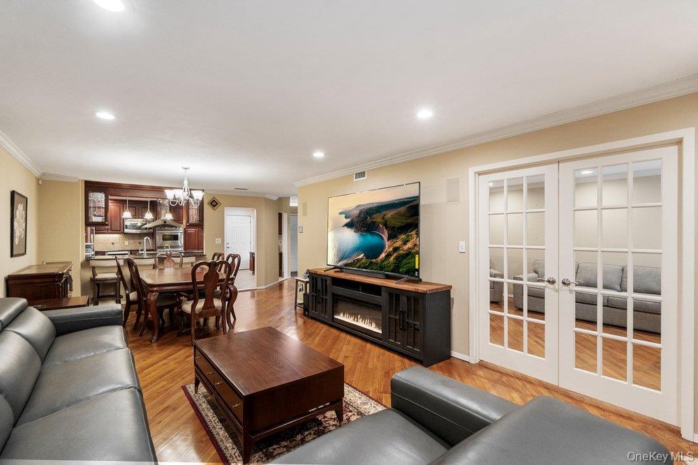 Open-concept living space featuring wood-finish flooring, recessed lighting, and crown molding