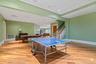 Spacious open-concept recreation area featuring wood-finish flooring, recessed lighting, and a drop ceiling