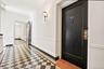 Entryway featuring checkered flooring, a black front door with brass hardware, a wall sconce, white walls with wainscoting, and a framed doorway