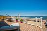 Expansive outdoor deck featuring wood-finish flooring, white railing, and waterfront access
