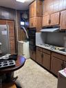 Kitchen featuring light countertops, wood walls, refrigerator, wall oven, and washer / dryer