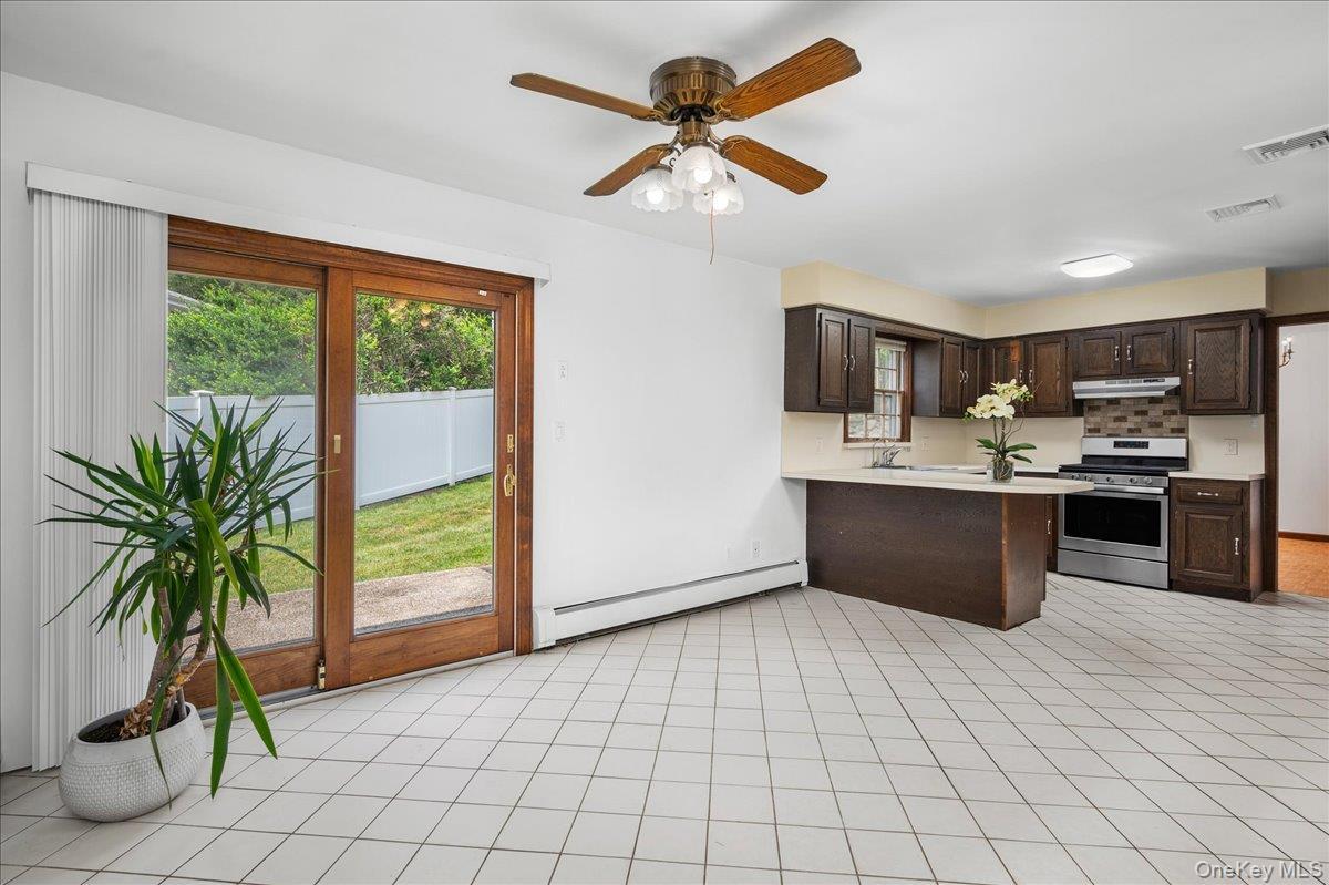 Kitchen area featuring a breakfast bar with light-toned countertops, dark wood-finish cabinetry, and stainless steel appliances