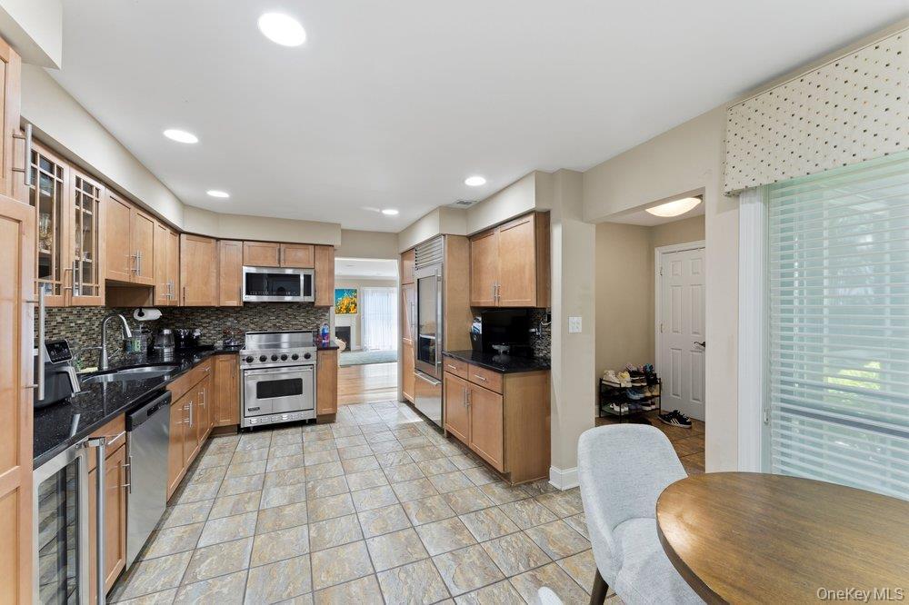 Kitchen featuring wood cabinetry, dark countertops, tiled backsplash, and stainless steel appliances