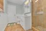 Bathroom with a shower stall, vanity, stone tile flooring, and a wainscoted wall