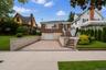 Brick exterior with a white garage door, paved driveway, and stone retaining walls