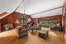 Living area with plenty of natural light, lofted ceiling, wooden walls, light wood-style flooring, and a skylight