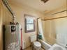 6 - Bathroom featuring water heater, toilet, a sink, and shower / bath combo with shower curtain