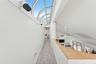 Corridor with light carpet, high vaulted ceiling, and a healthy amount of sunlight