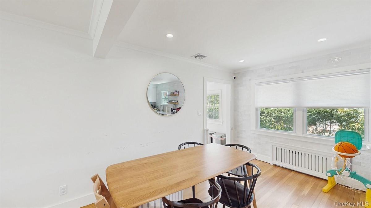 Dining room with crown molding, visible vents, radiator heating unit, and light wood finished floors