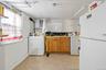 Kitchen with freestanding refrigerator, brown cabinets, washer / clothes dryer, and white cabinets
