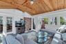 Living room with wood ceiling, an AC wall unit, and a ceiling fan