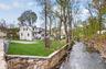 Flat backyard bordered by a peaceful channel of the Mamaroneck River, creating a unique natural setting.