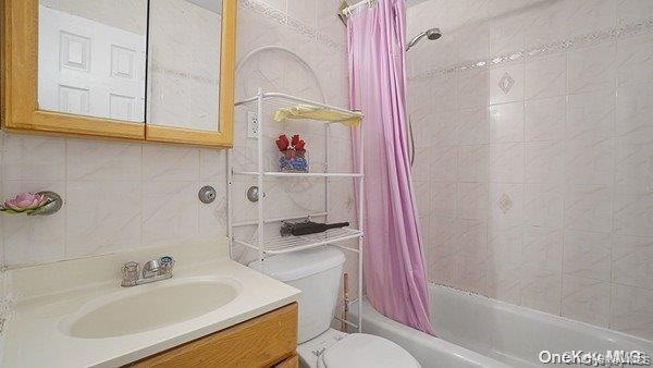 Full bathroom with vanity, shower / tub combo, tile walls, and decorative backsplash