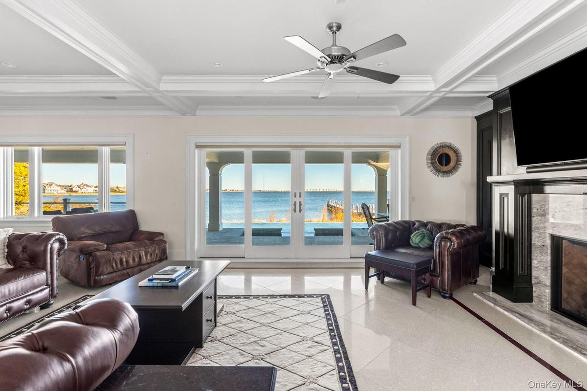 Living room with inlaid floor details, coffered ceiling, french doors, beamed ceiling, and ornamental molding