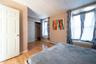 Bedroom with a drop ceiling, a baseboard heating unit, wood-type flooring, and a closet