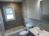 Bathroom featuring shower combination, tile walls, vanity, and recessed lighting