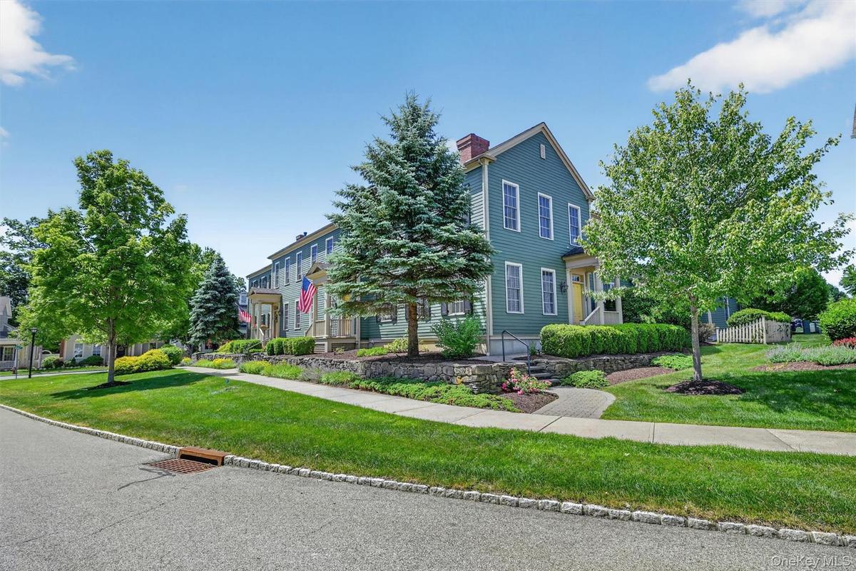Beautiful landscaping, stone walls, and tree-lined sidewalks create a peaceful approach to the home.