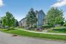 Beautiful landscaping, stone walls, and tree-lined sidewalks create a peaceful approach to the home.