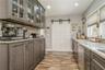 Kitchen featuring light stone countertops, light wood-type flooring, dark brown cabinetry, and a barn door