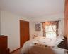 Bedroom featuring neutral wall tones, a double window with natural light, and a bi-fold louvered closet door
