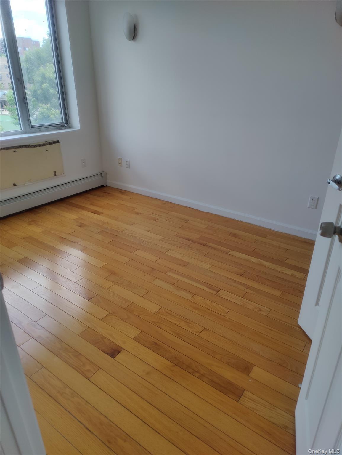Unfurnished room featuring baseboard heating and light wood-style floors