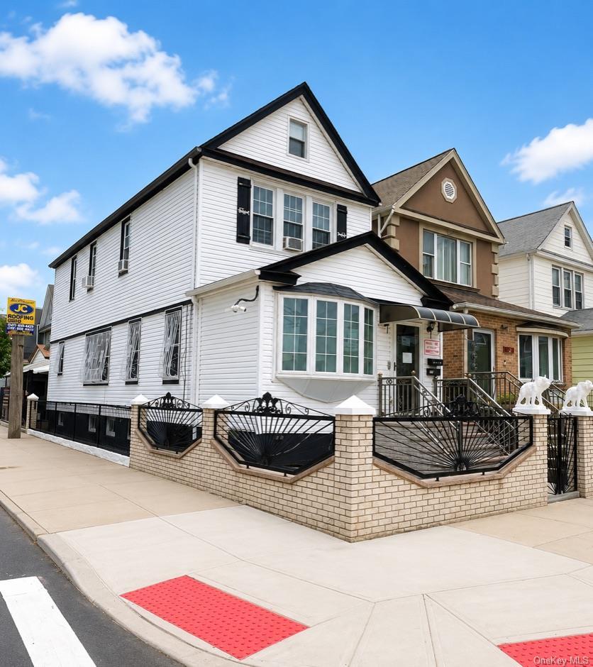 White siding exterior with a prominent bay window, contrasting black trim, and a gabled roofline