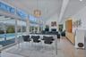Dining room with high vaulted ceiling, light wood finished floors, a glass covered fireplace, and a healthy amount of sunlight