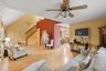 Living area featuring vaulted ceiling, wood finished floors, a ceiling fan, and stairway