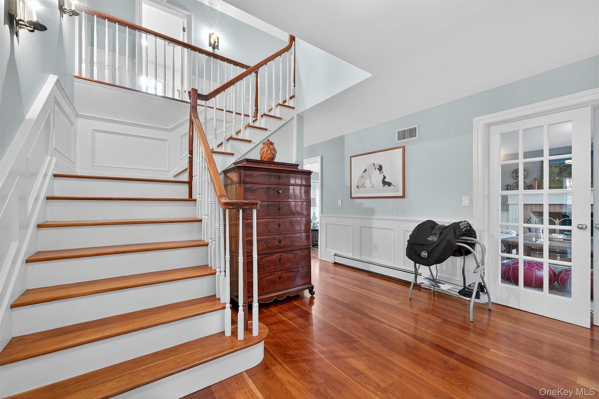 Staircase with a decorative wall, wainscoting, wood finished floors, and a baseboard radiator
