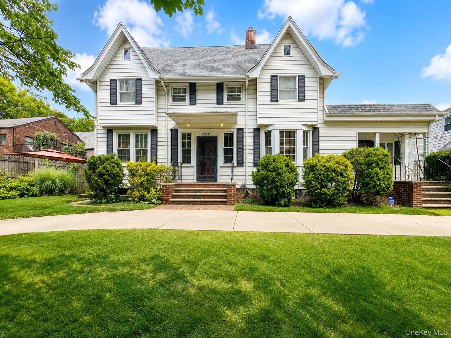 Stunning front façade highlighted by classic architectural styling, symmetrical design, and mature landscaping. The expansive lawn, inviting covered e