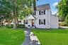Colonial-style house featuring roof with shingles and a front yard