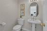 Pedestal sink with brushed nickel faucet, oval mirror, and three-light vanity fixture