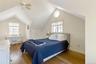 Bedroom with light wood-style floors, ceiling fan, multiple windows, and vaulted ceiling