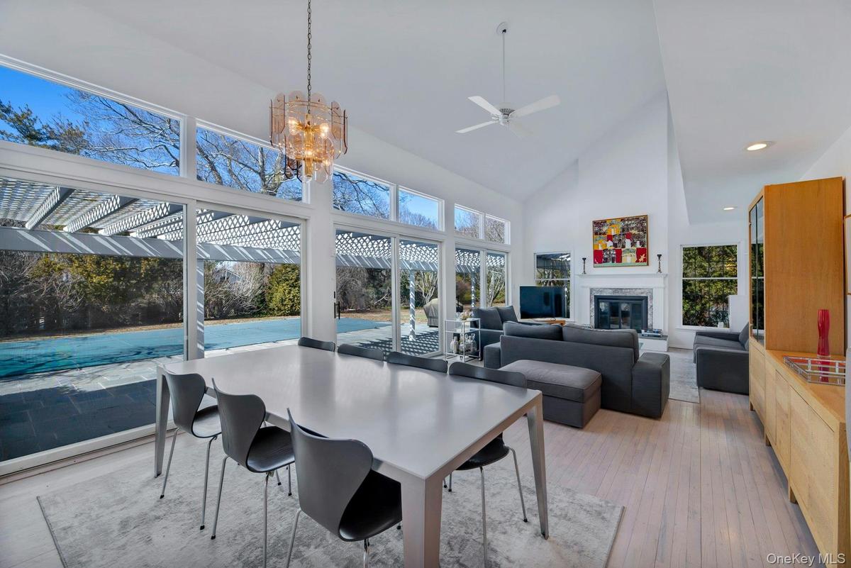 Ideal entertaining Space: Living room and dining area flanked by wall to wall glass sliders to patio, pool, tennis with a wood burning fireplace, dren