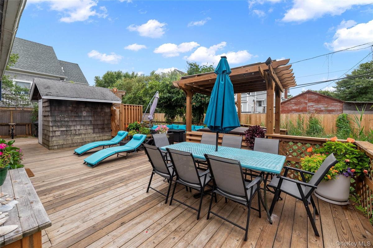 Wooden deck with outdoor dining area, a fenced backyard, and a storage unit