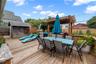 Wooden deck with outdoor dining area, a fenced backyard, and a storage unit