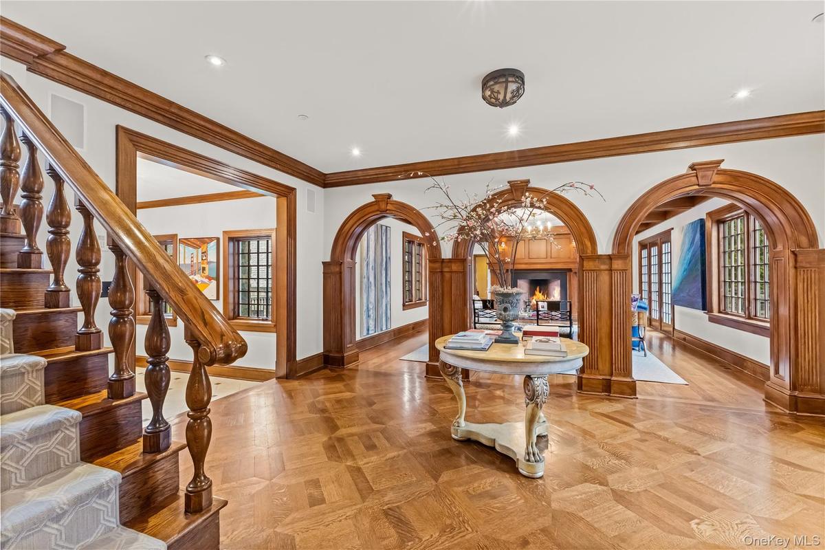 Entryway with arched walkways, detailed molding, parquet flooring, a warm lit fireplace, and recessed lighting