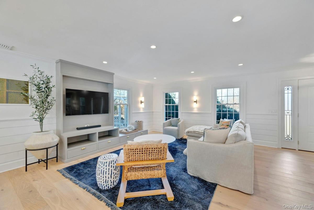 Living area featuring light wood-style flooring, crown molding, wainscoting, and recessed lighting