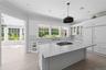 Kitchen featuring decorative backsplash, light stone counters, white cabinets, crown molding, and plenty of natural light