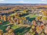 Aerial view of property and surrounding area featuring a forest