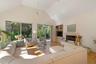 Living area featuring high vaulted ceiling, a tiled fireplace, light wood finished floors, built in features, and ceiling fan