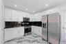 White cabinetry, black countertops with white veining, stainless steel appliances, and recessed lighting
