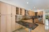 Kitchen featuring extensive light wood cabinetry, stone-finish countertops, and a tiled backsplash
