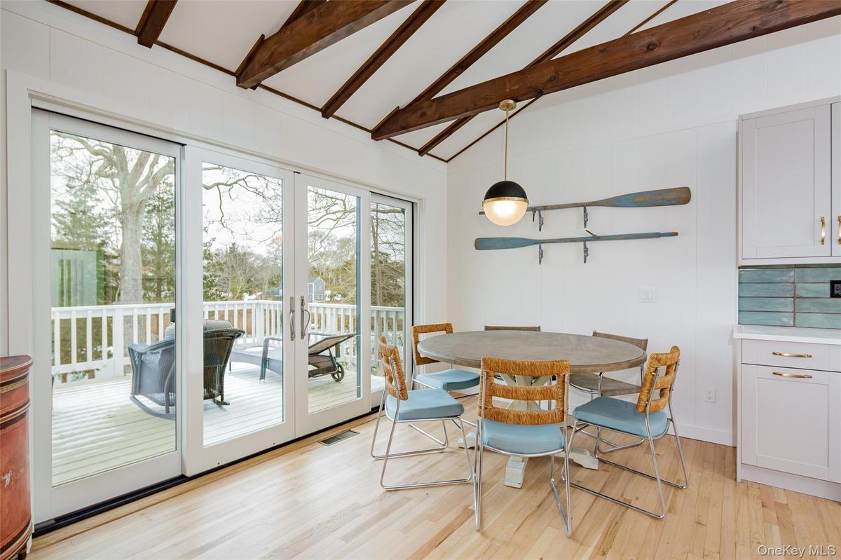 Dining area featuring beam ceiling, light wood-style floors, french doors, and high vaulted ceiling