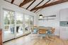 Dining area featuring beam ceiling, light wood-style floors, french doors, and high vaulted ceiling